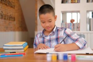 little asian child schoolboy drawing picture. children leisure activity at home